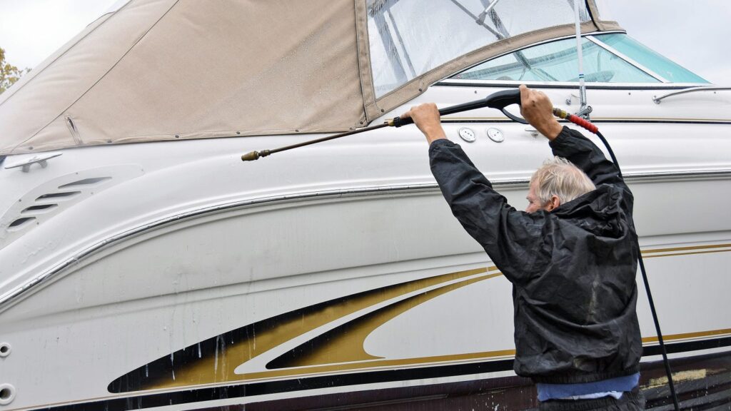 Man spraying boat with power washer